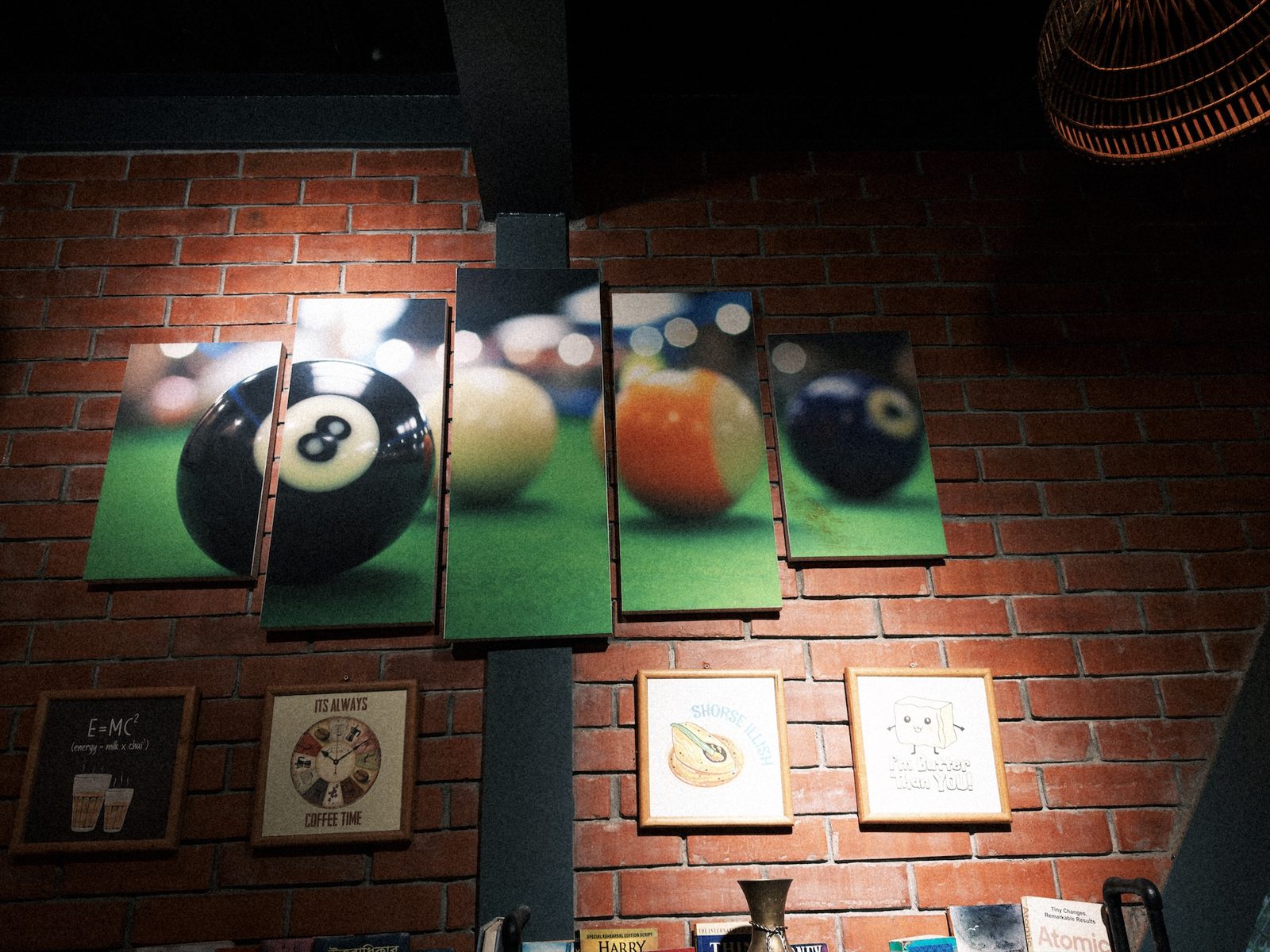 Pool-ball prints on a brick wall, with the two framed pictures below burnt out by a spotlight