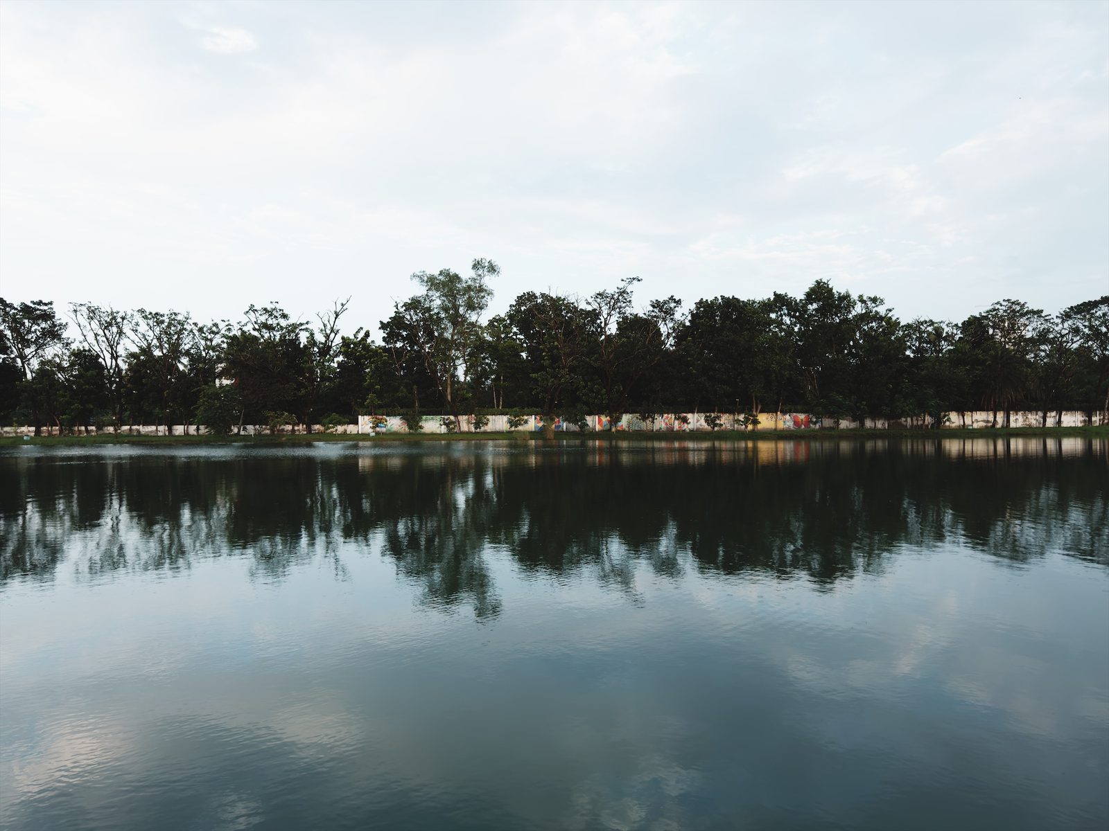 A lake with trees on the far bank and a pale, washed-out sky